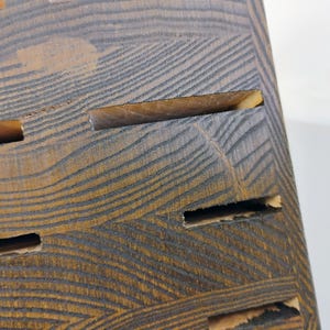 May include: A dark brown wooden knife block featuring a prominent natural wood grain pattern and multiple horizontal slots for storing kitchen knives. The block has a rectangular shape with a stained finish that highlights the wood texture.