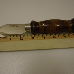 Puede incluir: Un pequeño cuchillo de uso general plateado con una hoja redondeada y un mango de madera. El cuchillo mide 7,6 cm de largo y tiene las palabras "Dexter, Southbridge, Mass." grabadas en la hoja.