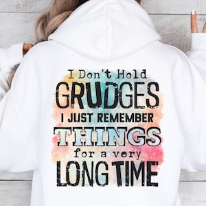 May include: A white hoodie with a colorful watercolor background and the text "I Don't Hold Grudges I Just Remember Things for a very Long Time" in black.