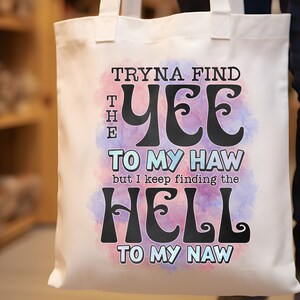 May include: White tote bag with the text "Tryna find the Yee to my Haw but I keep finding the Hell to my Naw" in black, over a watercolor-style pink and blue background. The bag has two handles.