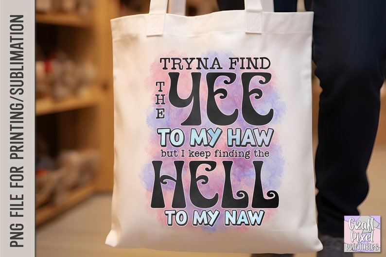 May include: White tote bag with the text "Tryna find the Yee to my Haw but I keep finding the Hell to my Naw" in black, over a watercolor-style pink and blue background. The bag has two handles.