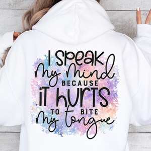 K&ouml;nnte beinhalten: Ein wei&szlig;er Hoodie mit einem bunten Aquarellhintergrund und dem Text "Ich sage meine Meinung, weil es weh tut, sich auf die Zunge zu bei&szlig;en".