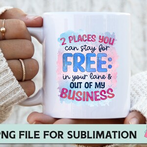 May include: White ceramic mug with a colourful watercolour design and the text "2 PLACES YOU can stay for FREE: in your lane & OUT OF MY BUSINESS".