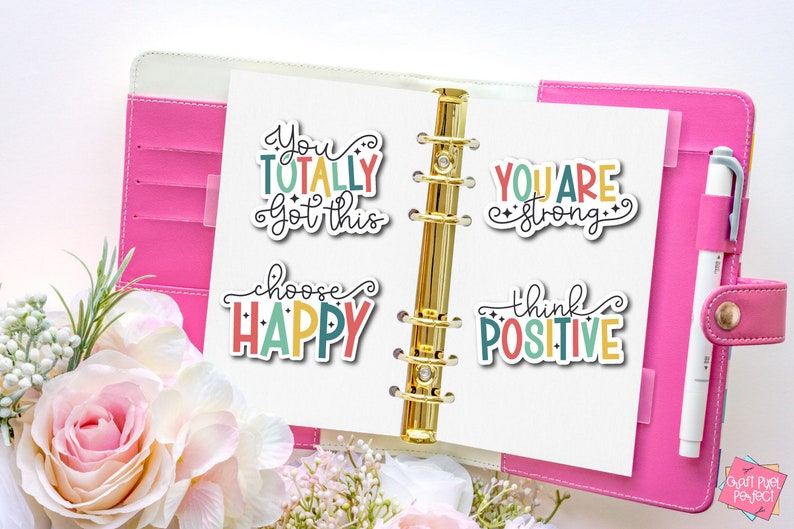 May include: Four colorful motivational stickers with positive messages: "You totally got this", "Choose Happy", "You are strong", and "Think Positive". The stickers are on a white page in a pink binder.