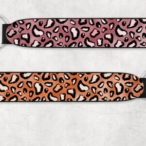 May include: Two keychains with black straps and silver key rings. The straps feature a leopard print pattern. One strap is pink and orange, the other is orange and brown.