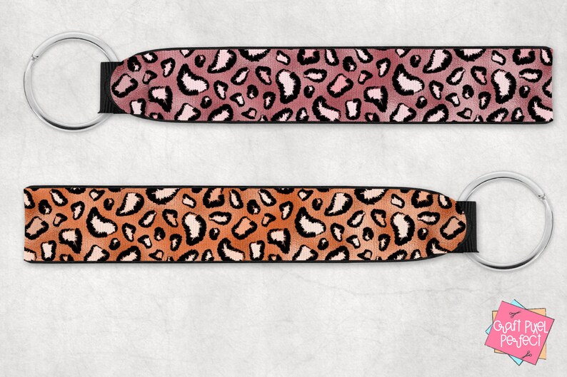 May include: Two keychains with black straps and silver key rings. The straps feature a leopard print pattern. One strap is pink and orange, the other is orange and brown.
