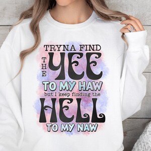 May include: White sweatshirt with the text "Tryna Find The Yee To My Haw but I keep finding the Hell To My Naw" in black, with a watercolor-style design in pink and purple. The sweatshirt is a PNG file for printing.