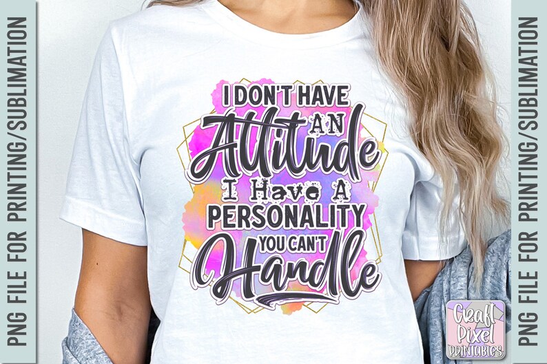 Puede incluir: Camiseta blanca con el texto "I don't have an attitude, I have a personality you can't handle" en escritura negra. El texto est&aacute; sobre un fondo de acuarela colorido con un marco geom&eacute;trico dorado.