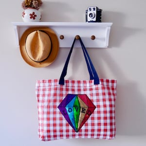 May include: Red and white gingham tote bag with a rainbow sequined diamond and the word "LOVED" in black lettering.