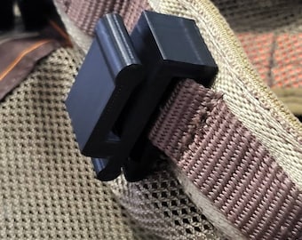May include: A black plastic clip attached to a brown strap. The strap is attached to a beige bag with a mesh panel.