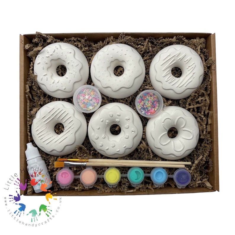 May include: A craft kit for painting doughnuts. The kit includes six white ceramic doughnuts, two paintbrushes, six small bottles of paint, two small containers of sprinkles, and a bottle of glaze.