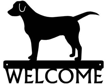May include: Black silhouette of a dog standing on a metal sign that says "WELCOME".