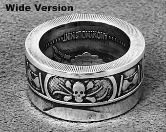 May include: A silver ring with a skull and crossbones design. The ring is engraved with the words "Anonymous Mint".