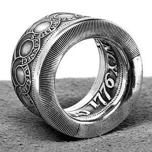 May include: A silver ring made from a 1776 coin. The ring features the inscription "RISING SUN" and "1776" on the outside of the band.