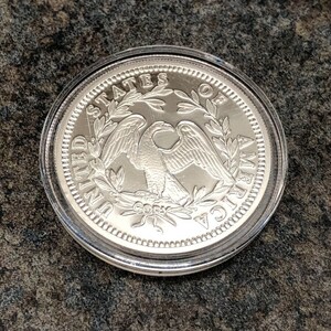 Puede incluir: Una moneda plateada con un &aacute;guila y la inscripci&oacute;n "UNITED STATES OF AMERICA". La moneda est&aacute; dentro de un estuche de pl&aacute;stico transparente. La palabra "COPY" tambi&eacute;n es visible.