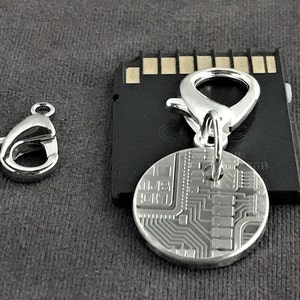 May include: Silver key chain with a circuit board design charm and a silver lobster clasp.