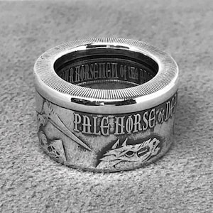 May include: A silver ring with a detailed design of a horse's head and the words "Pale Horse of Death".