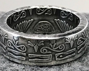 May include: Silver ring with an eye of Horus design. The ring is decorated with intricate patterns and symbols.