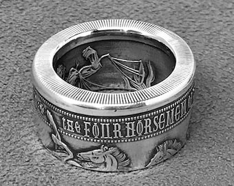 May include: A silver ring with a design of four horses and the text "The Four Horsemen".
