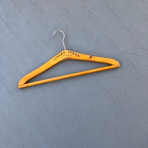 May include: A wooden clothes hanger with a metal hook. The hanger is engraved with the text "GUNNAR JANSON,  Mennkonfektion, Linköping".