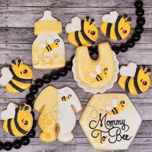 May include: A set of nine yellow and black bee-themed sugar cookies decorated with honeycombs and the text "Mommy To Bee".