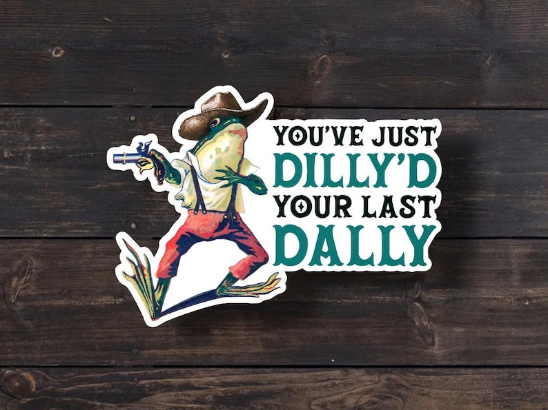 May include: A sticker featuring a cartoon frog wearing a cowboy hat and holding a gun. The text on the sticker reads "You've just dilly'd your last dally."