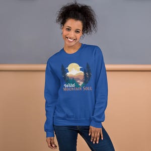 May include: A royal blue sweatshirt with a graphic of a mountain landscape with a sun and the text "Wild Mountain Soul".