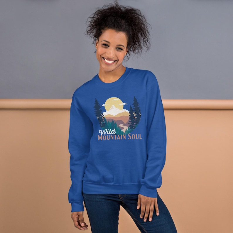 May include: A royal blue sweatshirt with a graphic of a mountain landscape with a sun and the text "Wild Mountain Soul".