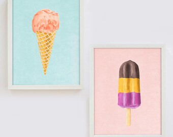 May include: Two framed prints of ice cream treats. The first print features a pink ice cream cone on a light blue background. The second print features a multi-colored popsicle on a pink background.