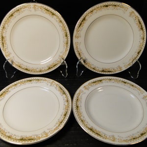 May include: Set of four white ceramic salad plates with a gold and green floral border.