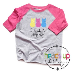 May include: A gray and pink raglan t-shirt with a graphic of three yellow, pink, and blue Peeps and the text "Chillin' with my peeps".