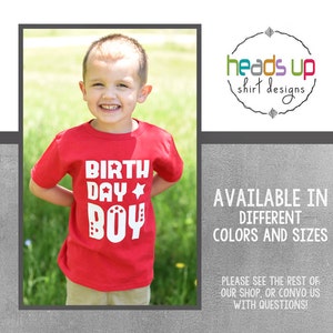 Pode incluir: Uma camiseta vermelha com texto branco que diz "BIRTH DAY BOY" com uma estrela e pequenas estrelas ao redor do texto. A camiseta está sendo usada por um menino pequeno.