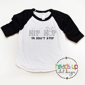 May include: White and black baseball tee shirt with the text "Hip Hop Ya Don't Stop" and a bunny rabbit graphic.