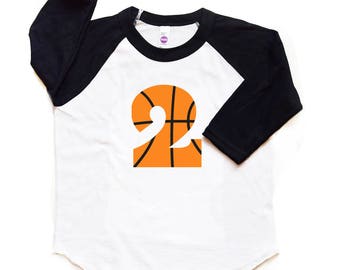 Può includere: Maglietta da baseball bianca e nera con maniche raglan e un numero 2 a forma di palla da basket arancione sul davanti.