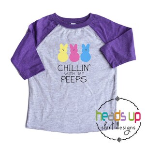 May include: A grey and purple raglan t-shirt with a graphic of three colorful Peeps and the text "Chillin' with my peeps".