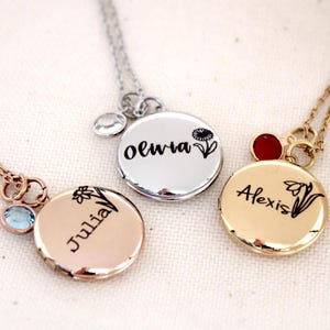 May include: Three silver, gold, and rose gold necklaces with engraved locket pendants. Each locket has a different name engraved on it: Olivia, Alexis, and Julia. Each locket also has a small flower design and a small gemstone.