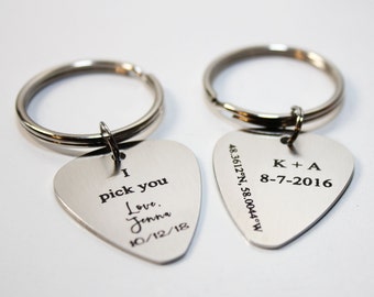 May include: Two silver guitar pick keychains with engraved messages. One keychain says "I pick you Love, Jenna 10/12/18". The other keychain says "K+A 8-7-2016 48.3612°N, 58.0044°W".
