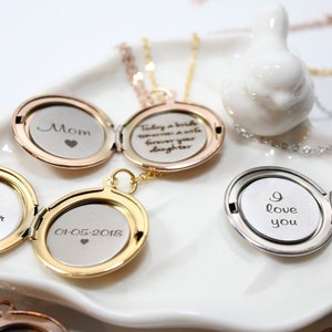 Puede incluir: Colgantes abiertos en oro, oro rosa y plata, cada uno con un mensaje grabado. Los colgantes, expuestos en una bandeja blanca, incluyen las palabras "Mom", "Amber" y "I love you".