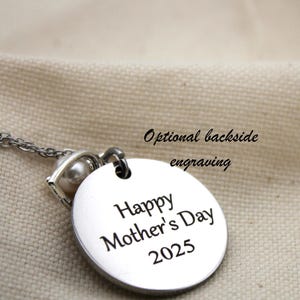 K&ouml;nnte beinhalten: Silberne Halskette mit einem runden Anh&auml;nger, auf dem "Happy Mother's Day 2025" steht. Der Anh&auml;nger hat einen kleinen Perlenanh&auml;nger. Optionale Gravur auf der R&uuml;ckseite.