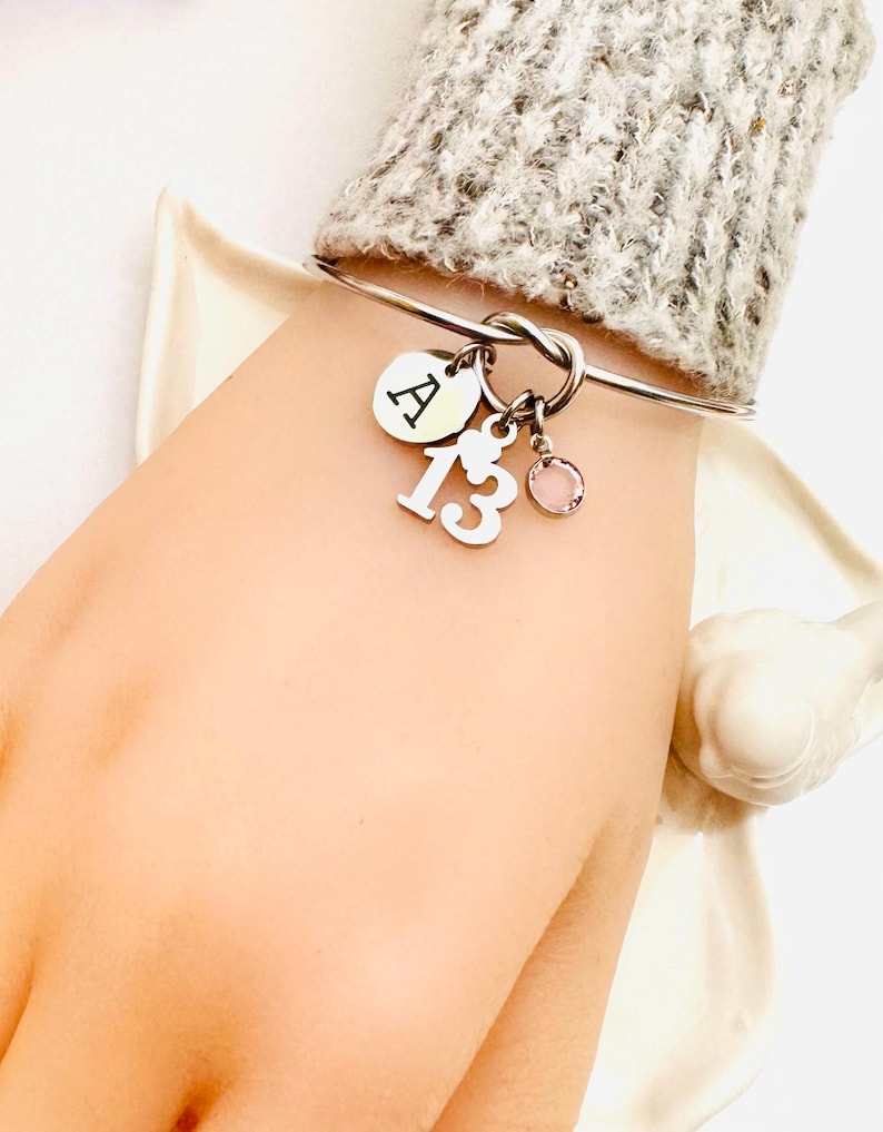 a bracelet that has a charm with the letter of the alphabet and another charm with the number 13