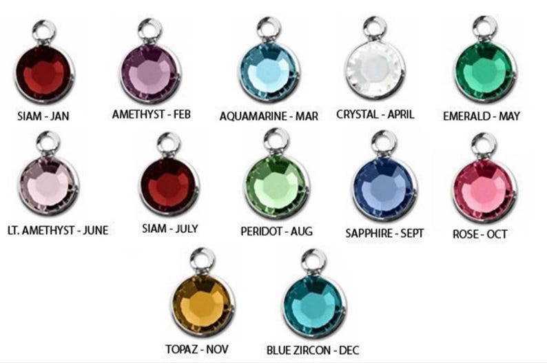 Puede incluir: Una colecci&oacute;n de doce colgantes redondos de piedras preciosas en varios colores, cada uno con un lazo plateado. Los colores incluyen rojo, morado, azul, transparente, verde, rosa y amarillo, con los nombres de los meses correspondientes: Ene, Feb, Mar, Abr, May, Jun, Jul, Ago, Sep, Oct, Nov, Dic.