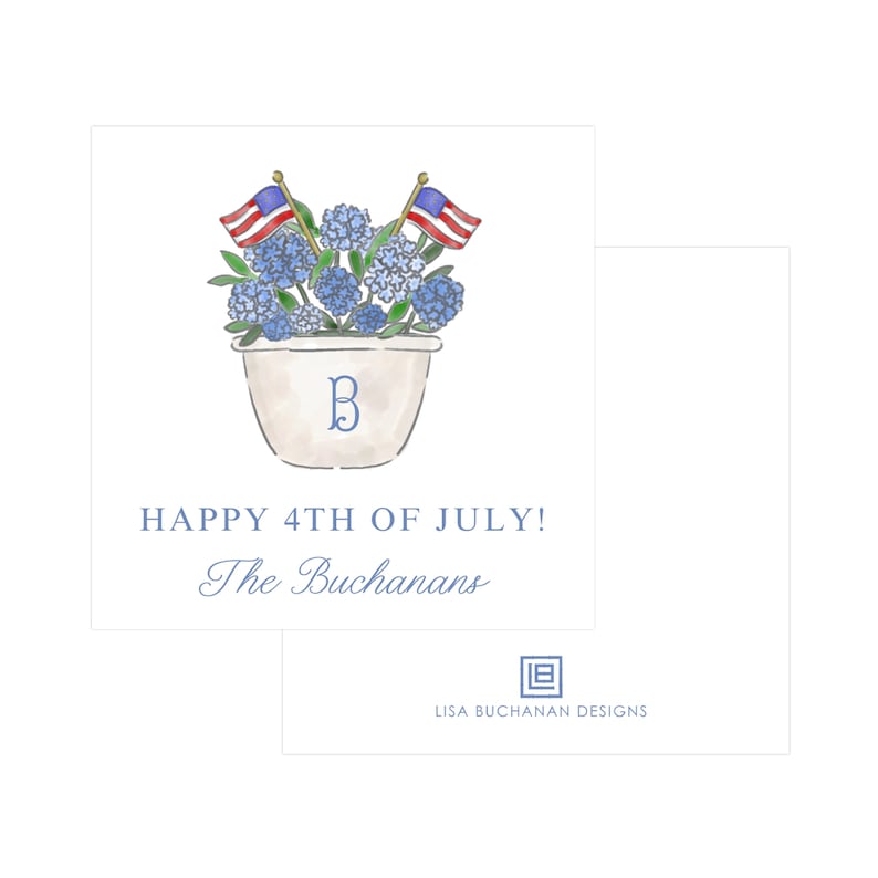 May include: A white planter with blue hydrangeas and two small American flags. The planter has a letter "B" painted on it. The text "HAPPY 4TH OF JULY! The Buchansans" is below the planter. The text "LISA BUCHANAN DESIGNS" is below the planter.