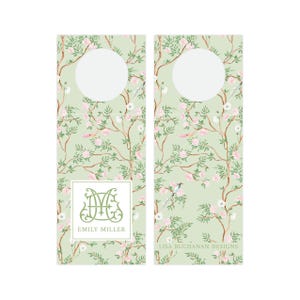 May include: Two green and white floral patterned bottle tags with a circle cut out for the neck of a bottle. The left tag has a monogram with the initials "EM" and the name "Emily Miller" printed below. The right tag has the text "Lisa Buchanan Designs" printed below the circle.