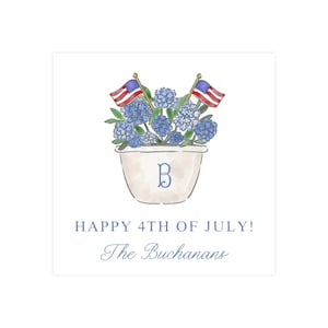 May include: A white planter with a blue "B" monogram is filled with blue hydrangeas and topped with two small American flags. The text "HAPPY 4TH OF JULY! The Buchansans" is below the planter.