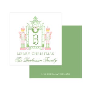 May include: A square white holiday card featuring a watercolor illustration of two pink and green nutcrackers flanking a bamboo-style pagoda frame with a green letter B and wreath. Text reads MERRY CHRISTMAS The Buchanan Family and LISA BUCHANAN DESIGNS.