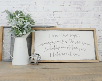 May include: A wooden sign with white paint and black lettering. The sign reads "I have late night conversations with the moon. He talks about the sun. I talk about you."