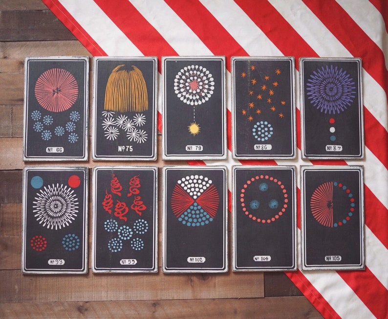 Peut inclure: Dix cartes encadr&eacute;es en noir et blanc avec diff&eacute;rents motifs de feux d'artifice. Chaque carte porte un num&eacute;ro et le mot "No." imprim&eacute; dessus. Les cartes sont dispos&eacute;es en deux rang&eacute;es de cinq.