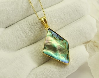 May include: A gold chain necklace with a diamond-shaped pendant featuring a green, blue, and iridescent abalone shell.