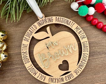 May include: Wooden apple-shaped ornament with the text "Mrs. Brown" in gold lettering. The ornament is decorated with the words "Hard Working, Role Model, Supportive, Dedicated, Inspiring, Passionate, Mentor, Chaos Coordinator" around the edge.