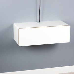 May include: White floating shelf with a cable management slot. The shelf is mounted on a gray wall.